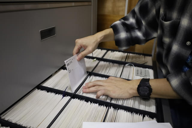 （画像上：3点）スチル写真の出庫の様子。可動式の保存棚を動かし、資料番号順リストを見ながらキャビネットから袋を取り出す