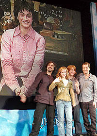 (後ろ)スクリーンに登場したダニエル・ラドクリフ (前列左より)会場で手を振るキュアロン監督、 エマ、ルパート、デビッド・ヘイマン