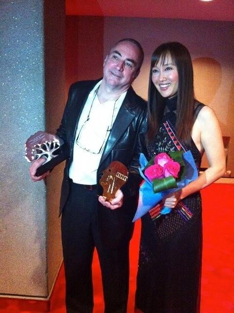 トロフィーを手に笑顔をのぞかせる クロード・ガニオン監督と工藤夕貴