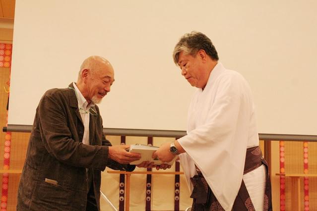春日大社宮司の花山院弘匡氏に 作品を手渡す本橋成一監督