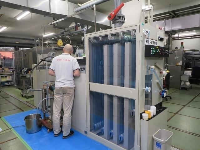 フィルムの染色作業中の機械を確認する柴田さん