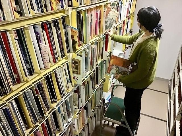 図書室 書庫のパンフレット棚で作業をする司書の笹沼さん