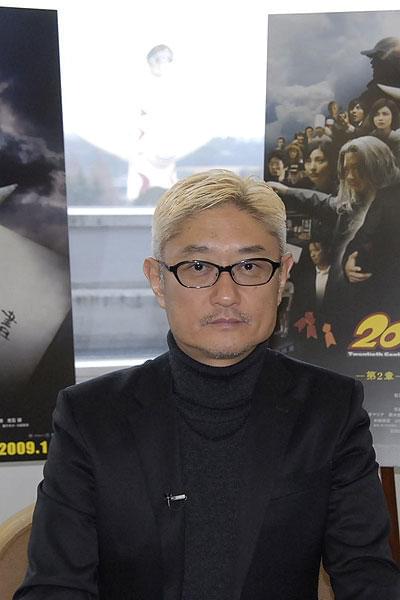 堤幸彦監督と後ろに見えるのが “太陽の塔”ならぬ“ともだちの塔”